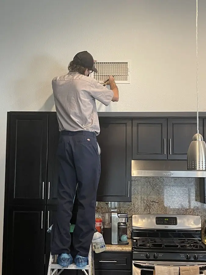 Technician inspecting an air vent during HVAC service in Hunters Creek